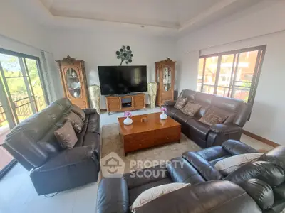 Luxurious living room with leather sofas and large TV, perfect for relaxation and entertainment.