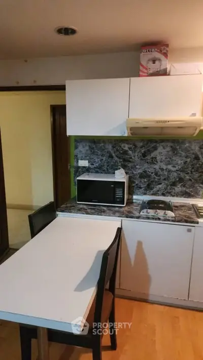 Cozy kitchen with modern appliances and marble backsplash in a compact layout.