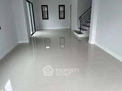Spacious modern living room with glossy tiled floors and staircase