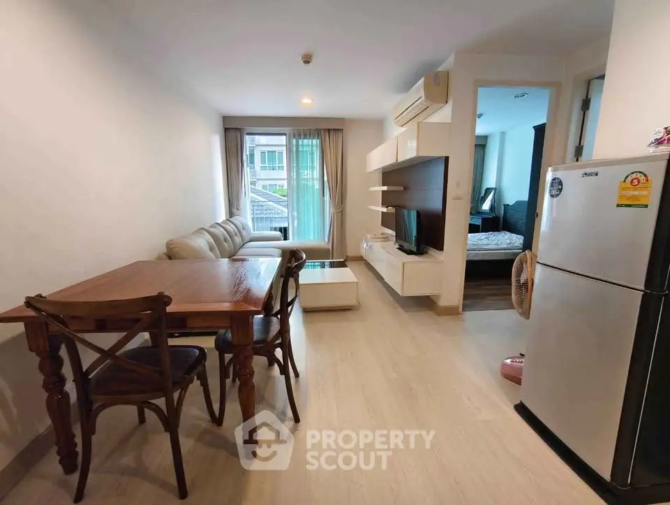 Modern apartment living room with cozy sofa, dining table, and open kitchen layout.