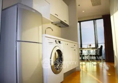 Modern kitchen with sleek appliances and dining area with large windows offering natural light.
