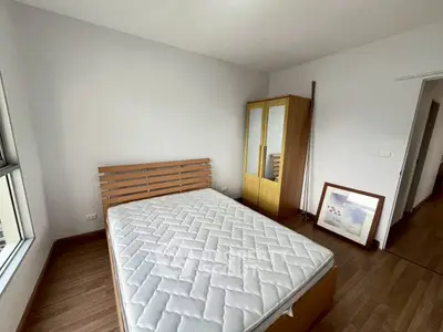 Cozy bedroom with wooden flooring and a large window for natural light.
