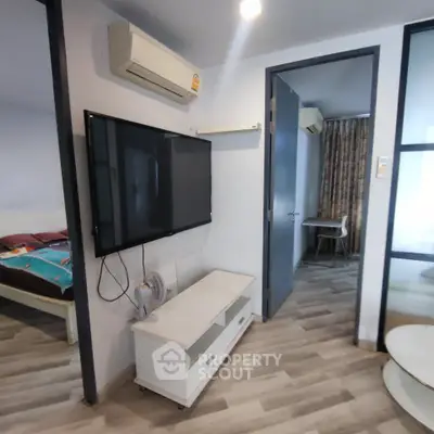 Modern apartment interior with wall-mounted TV and air conditioning, featuring stylish flooring and cozy bedroom view.