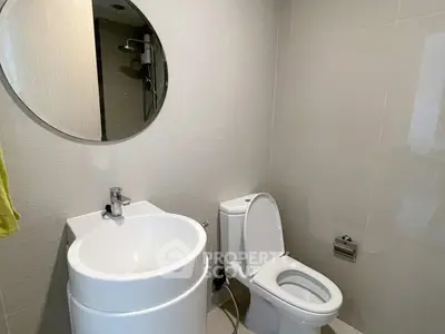 Modern bathroom with round mirror and sleek fixtures in contemporary apartment.