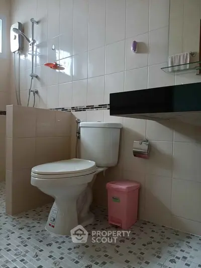 Modern bathroom with tiled walls, shower, and toilet, featuring a sleek design.