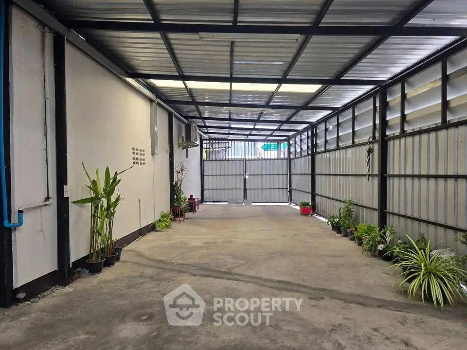 Spacious covered parking area with potted plants and metal roofing.