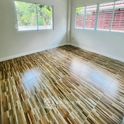 Spacious room with large windows and stylish wood-patterned tile flooring.