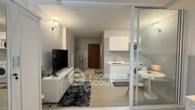 Modern open-plan living room with kitchen and dining area, featuring sleek furniture and bright lighting.