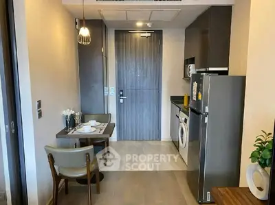 Modern apartment interior with compact kitchen and dining area, featuring sleek appliances and stylish decor.
