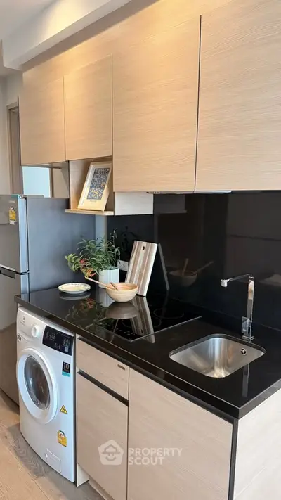 Modern kitchen with sleek black countertop and built-in appliances in stylish apartment.