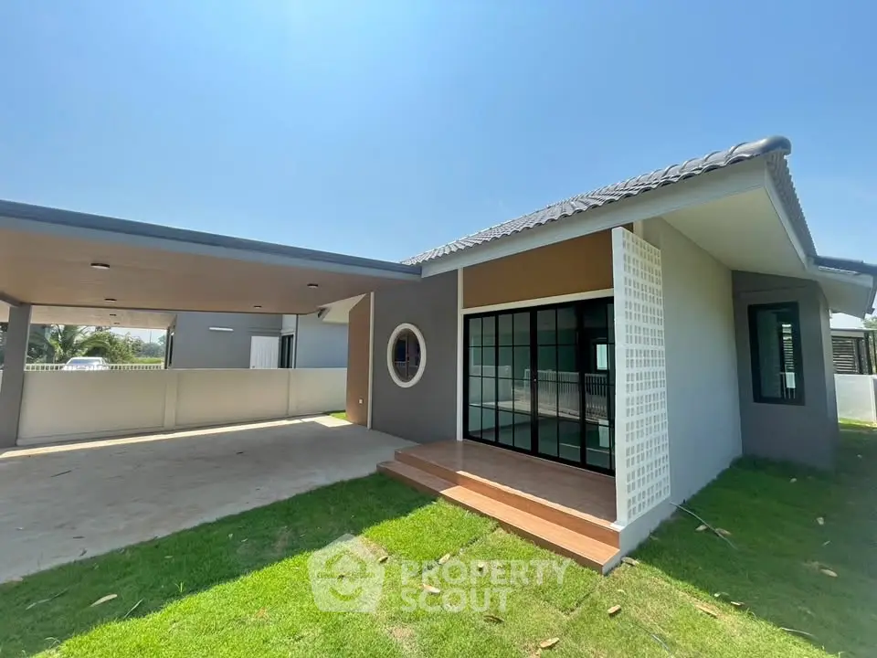 Modern single-story house with carport and lawn under clear blue sky.