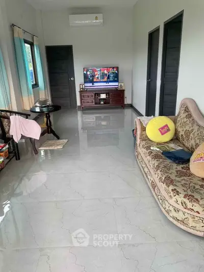 Spacious living room with elegant sofa and modern TV setup, perfect for relaxation and entertainment.