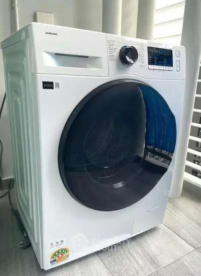 Modern Samsung washing machine in sleek laundry area with natural light.
