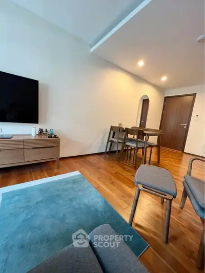 Modern living room with wooden flooring, stylish furniture, and a large TV, perfect for relaxation.
