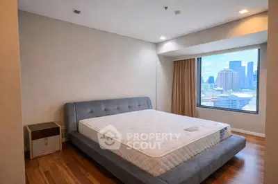 Spacious bedroom with city view and modern furnishings in high-rise apartment.