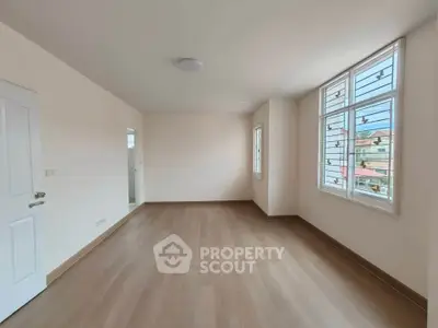 Spacious empty room with large windows and wooden flooring, perfect for customization.