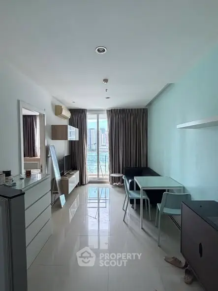 Modern living room with dining area and city view, featuring sleek furniture and large windows.