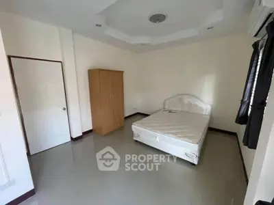 Spacious bedroom with minimalist decor and ample natural light, featuring a comfortable bed and wardrobe.