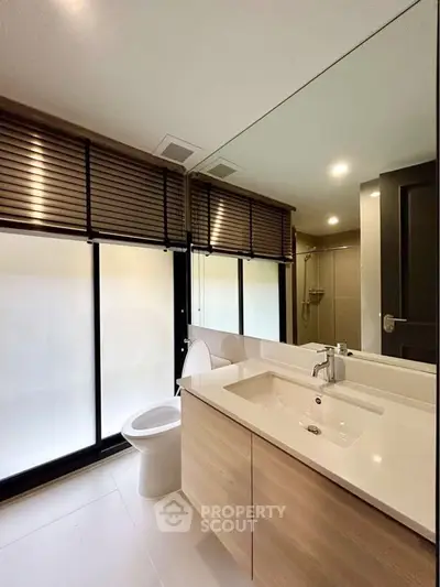 Modern bathroom with sleek design, featuring a large mirror and stylish fixtures.