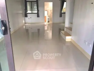 Spacious open-plan living area with glossy tiled floors and modern staircase.