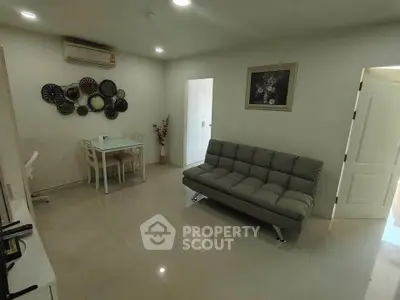 Modern living room with sleek sofa, dining area, and wall art in a cozy apartment.