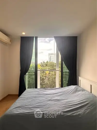Modern bedroom with large window and city view, featuring sleek design and natural light.