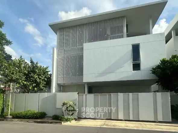 Modern minimalist white building with sleek facade and lush greenery