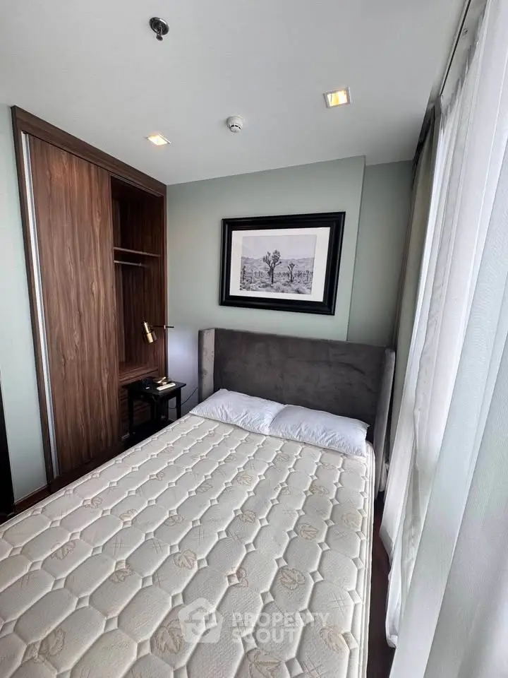 Cozy bedroom with modern design and ample natural light, featuring a stylish bed and built-in wardrobe.