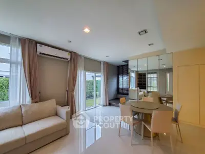 Modern living room with sleek design and dining area, featuring large windows and stylish furniture.