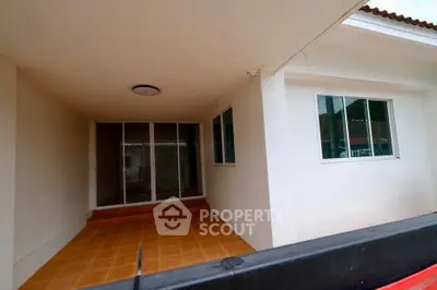 Spacious covered patio with sliding glass doors and tiled flooring in modern home.
