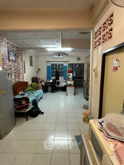 Cozy living room with tiled flooring and eclectic decor, featuring a fridge and comfortable seating.