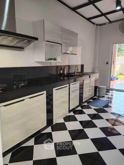 Modern kitchen with sleek cabinetry and black-and-white checkered flooring, featuring a gas stove and ample counter space.