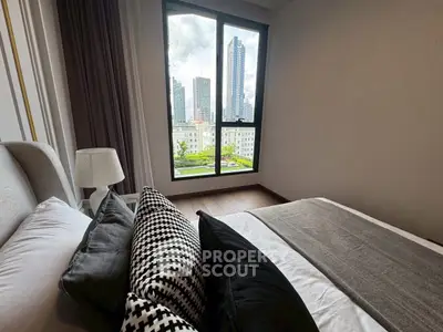 Modern bedroom with city view, featuring stylish decor and large window.
