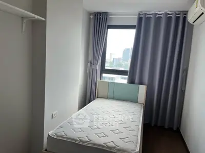 Cozy bedroom with a single bed and city view from the window.