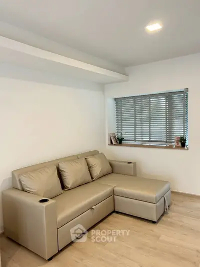 Modern living room with sleek beige sofa and window blinds, perfect for cozy relaxation.