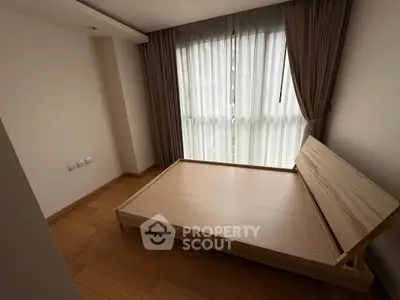Spacious bedroom with wooden flooring and large window for natural light.