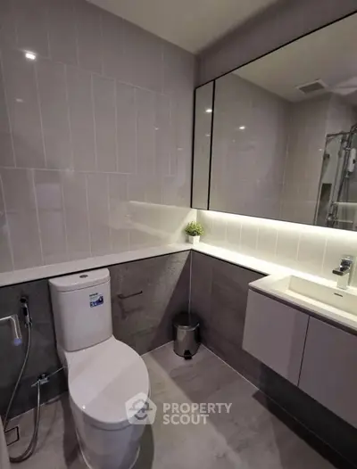 Modern bathroom with sleek design, featuring a large mirror and contemporary fixtures.
