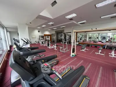 Spacious gym with modern equipment and large mirrors in a real estate property.