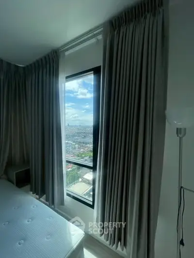 Bright bedroom with city view through large window and elegant curtains.