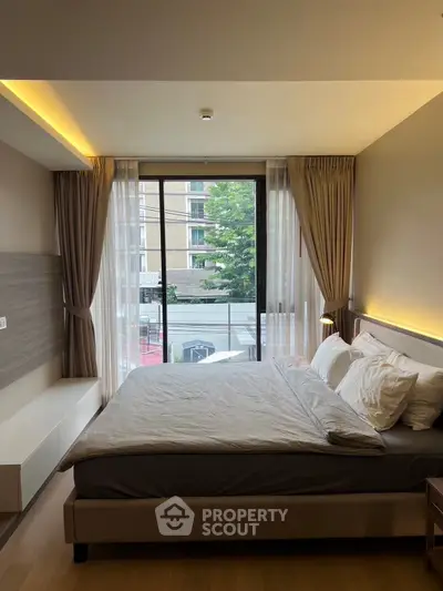 Modern bedroom with large window and elegant decor in urban apartment.
