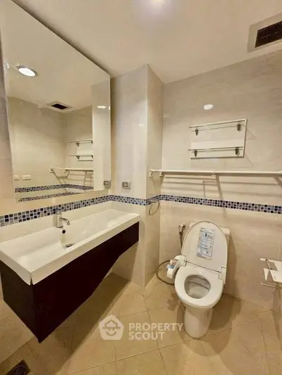 Modern bathroom with sleek fixtures and large mirror, featuring a stylish sink and toilet.