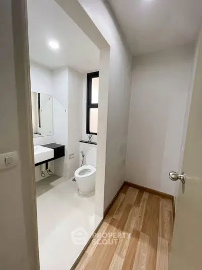 Modern bathroom with sleek design and natural light, featuring a toilet and stylish sink area.