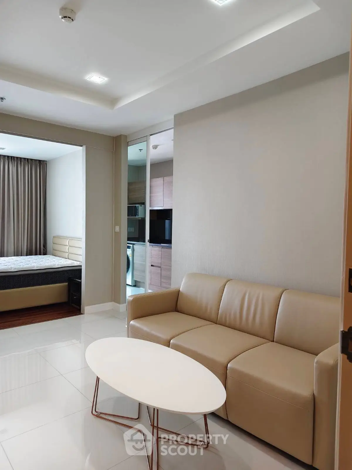 Modern apartment interior with cozy living room and adjacent bedroom, featuring sleek furniture and neutral tones.