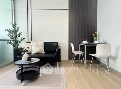 Modern living room with sleek black sofa, stylish dining set, and elegant decor in a contemporary apartment.