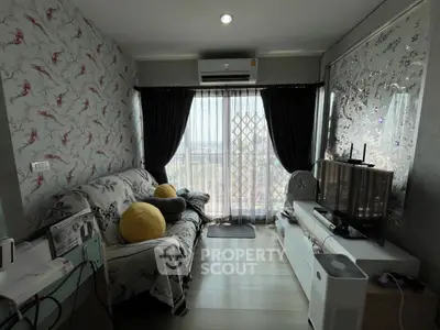 Charming living room with floral wallpaper, cozy sofa, and balcony view, perfect for relaxation.