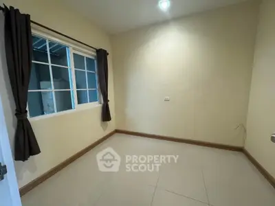 Spacious empty room with large window and tiled floor, perfect for customization.
