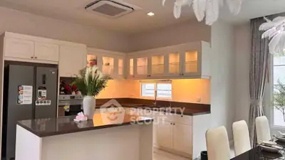 Modern kitchen with sleek countertops and elegant dining area, featuring built-in appliances and stylish decor.