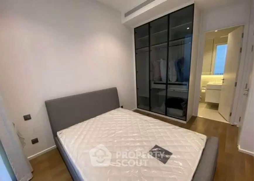 Modern bedroom with sleek wardrobe and ensuite bathroom in stylish apartment.