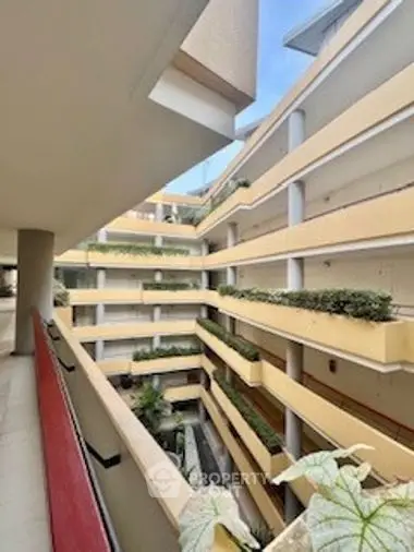 Spacious balcony with a view of a modern multi-level apartment complex, featuring lush greenery and contemporary architecture.