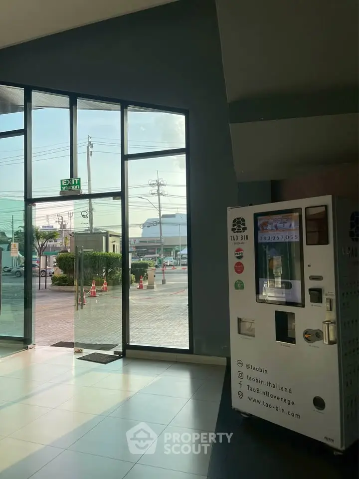 Modern building entrance with large glass doors and vending machine, offering a glimpse of the urban surroundings.